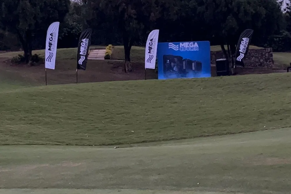 Cuatro banderas tipo pluma y un backwall montados en un campo de golf para un evento