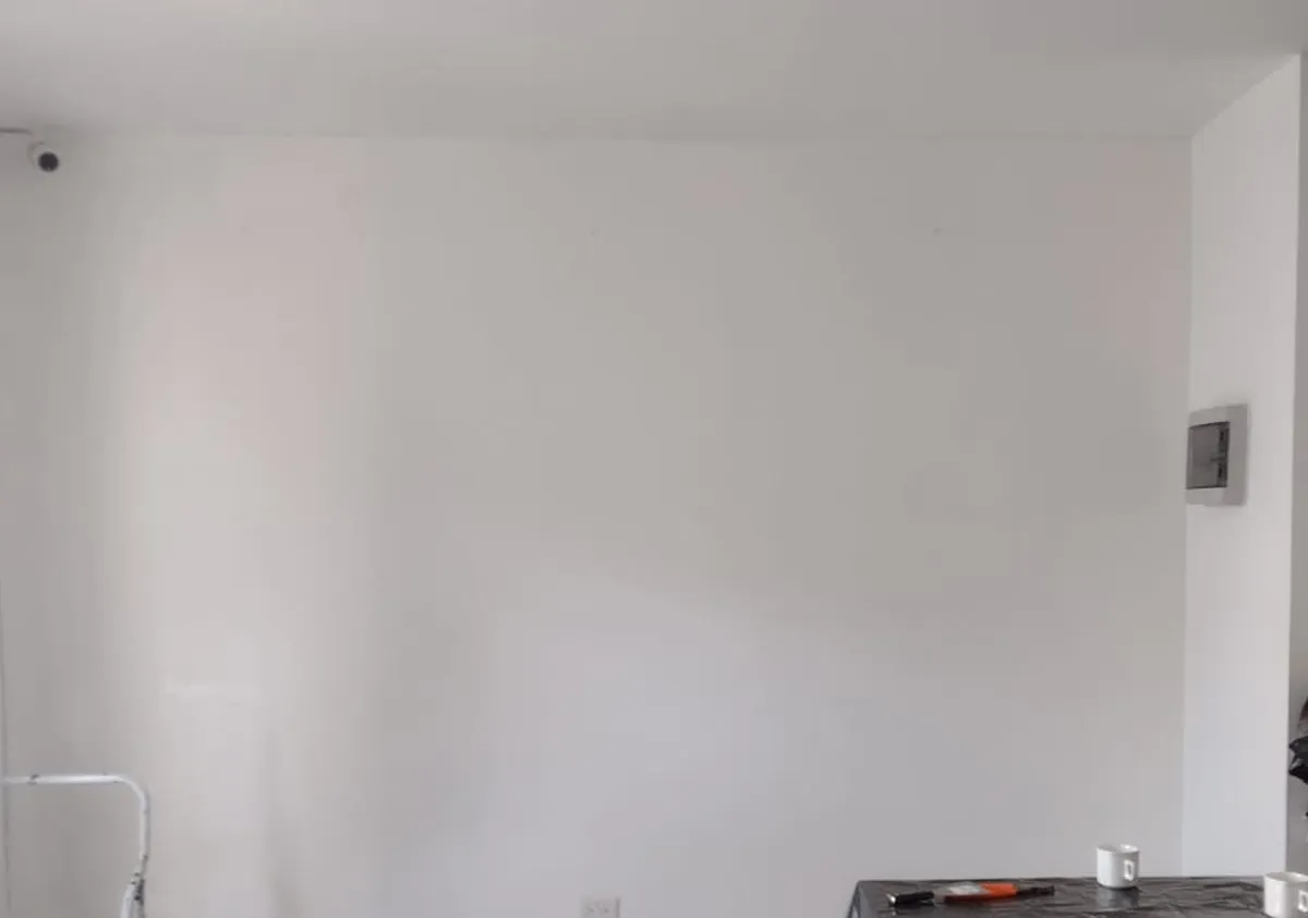 Pared blanca de una oficina vacía antes de instalar el vinil de corte, con mesas cubiertas durante el trabajo