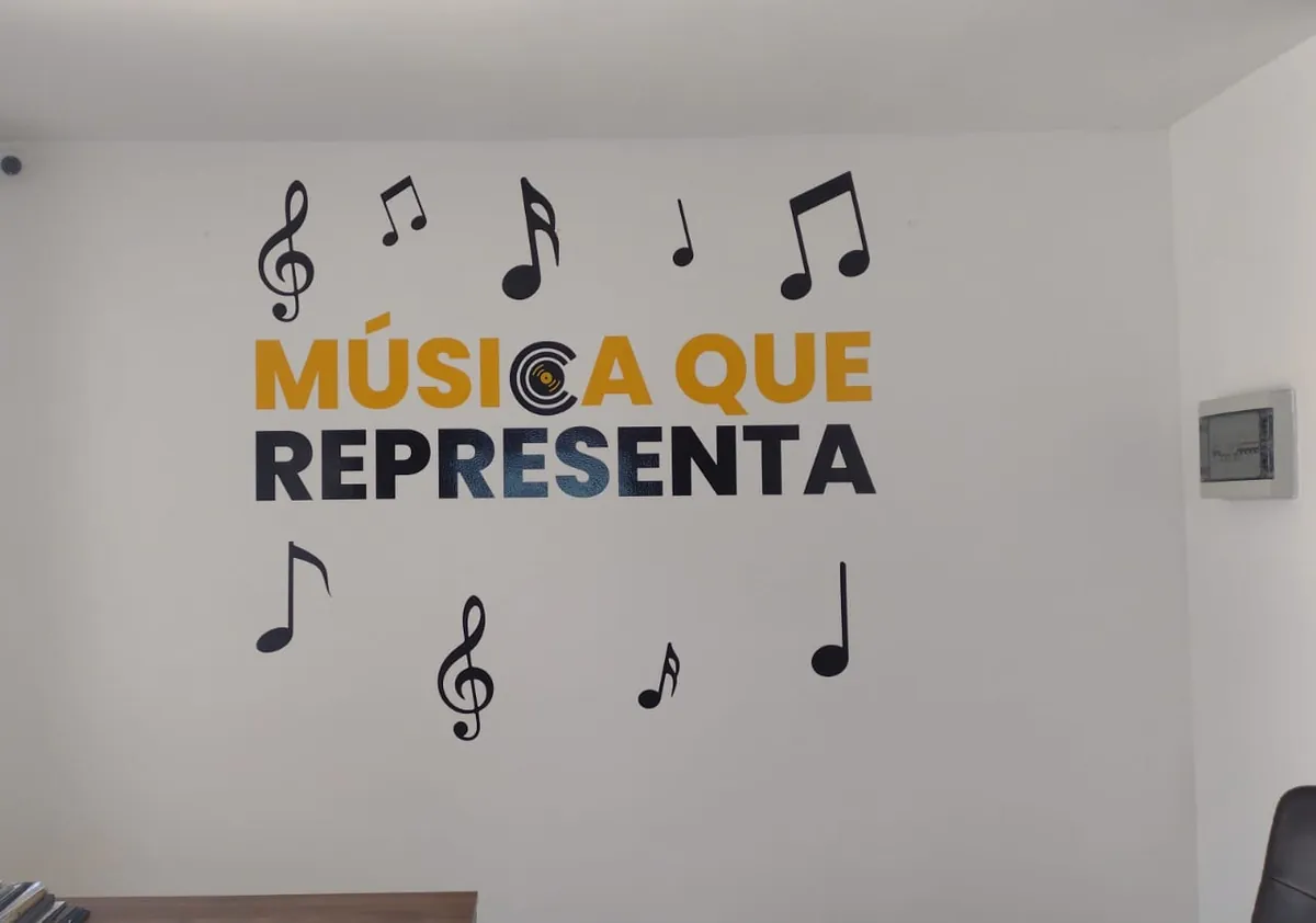 La misma pared de oficina ya terminada, con una frase y notas musicales en vinil de corte amarillo y negro