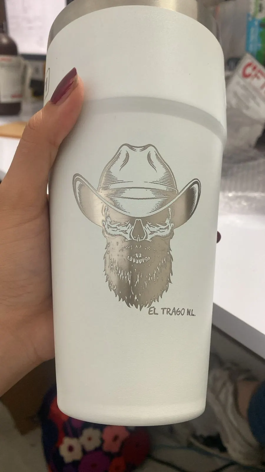 Termo blanco grabado con láser con ilustración de calavera, sostenido con la mano