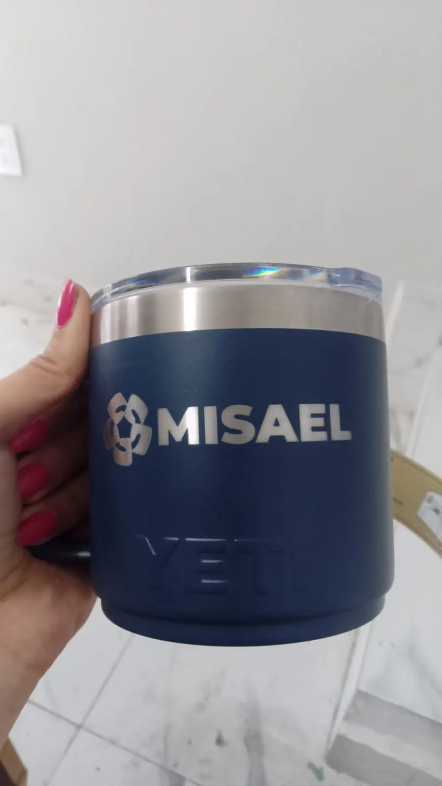 Termo azul marino grabado con láser con un nombre y un logotipo, sostenido con la mano