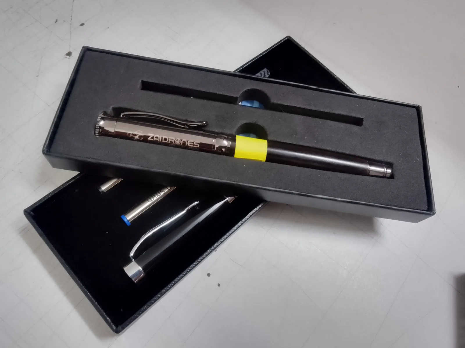 Pluma metálica grabada con láser con el logotipo de una empresa, presentada en estuche negro