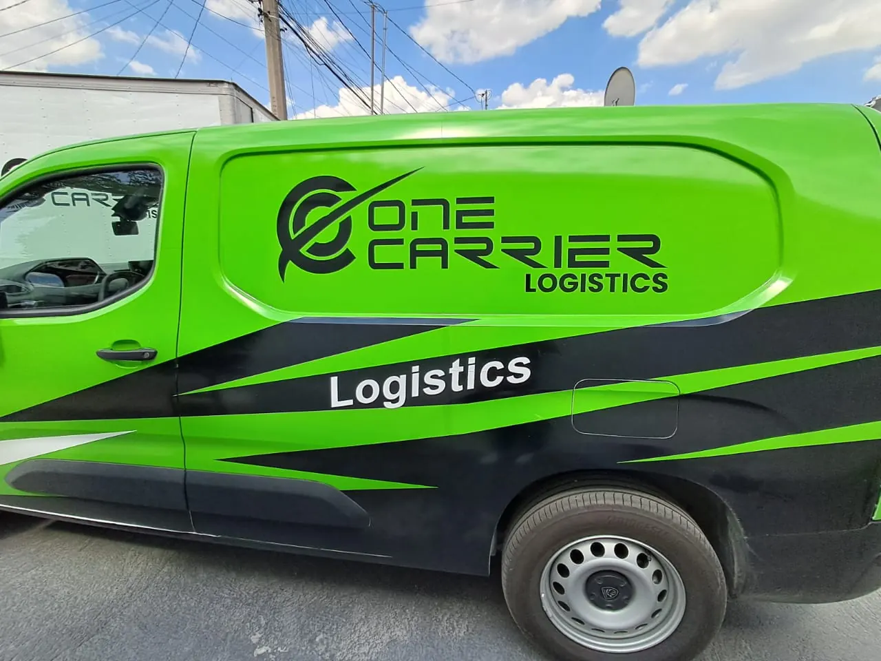 Costado de camioneta van rotulada en vinil verde y negro con logotipo de empresa de logística