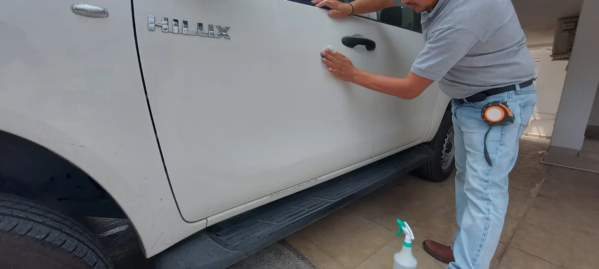 Instalador de Punto Clave aplicando vinil de corte en la puerta de una camioneta dentro del taller