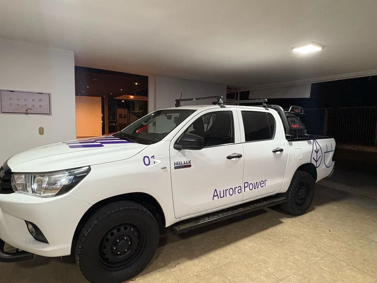 Camioneta pickup blanca con nombre de empresa y número de unidad en vinil de corte morado sobre las puertas