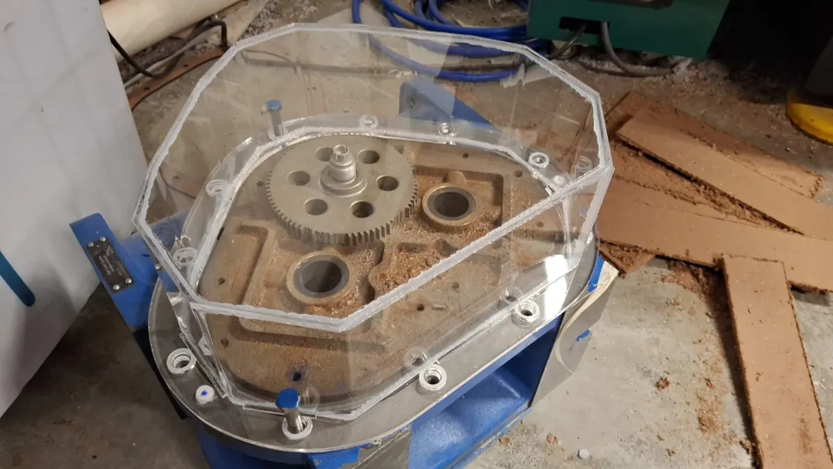 Tapa protectora de acrílico transparente atornillada sobre los engranes de una máquina, hecha a la medida