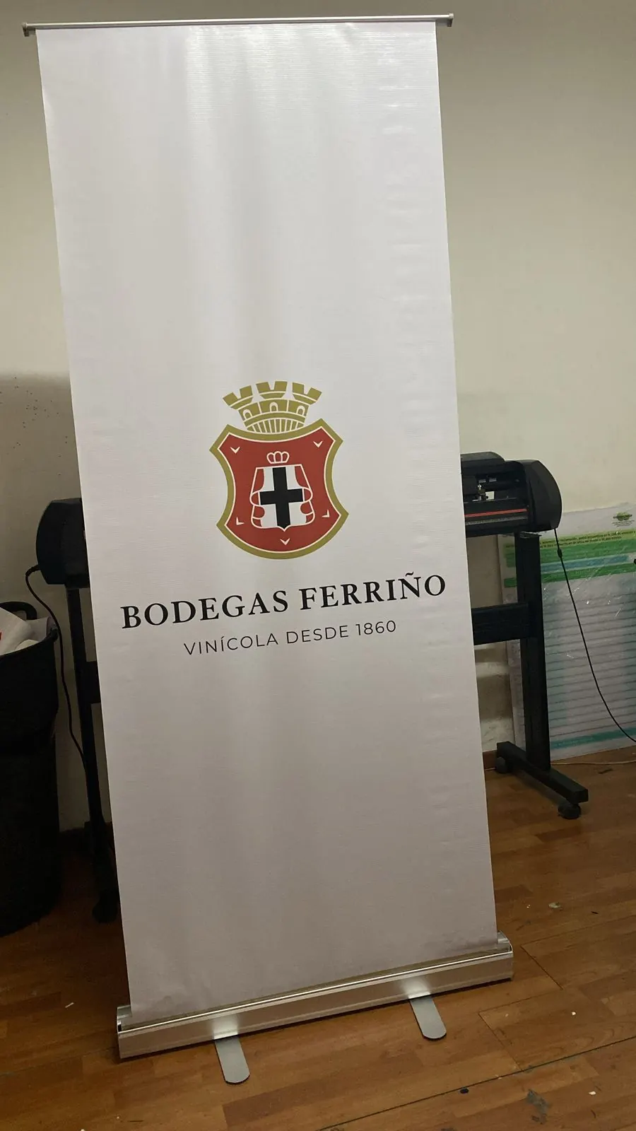 Banner roll-up blanco con escudo de bodega vinícola, listo para entregarse
