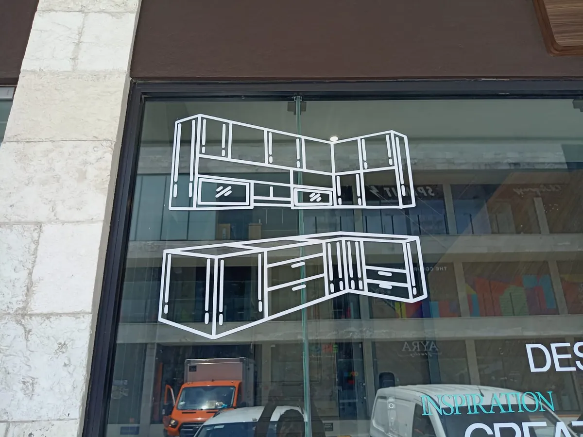Dibujo lineal de cocina integral en vinil de corte blanco aplicado sobre la vitrina de un estudio de diseño