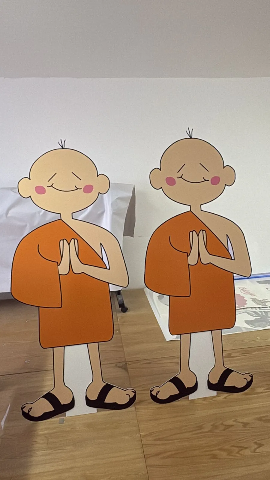 Dos figuras de personaje impresas y cortadas a forma en PVC con base, de pie en el taller