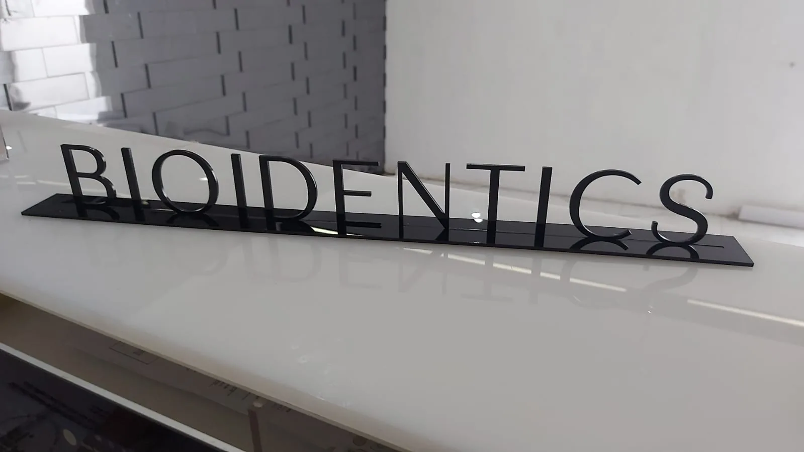 Letras de acrílico negro cortadas con láser montadas sobre una base, con borde pulido