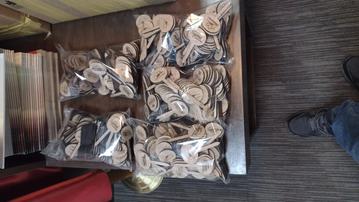Bolsas con cientos de piezas redondas de MDF con palito, cortadas y grabadas con láser por lote