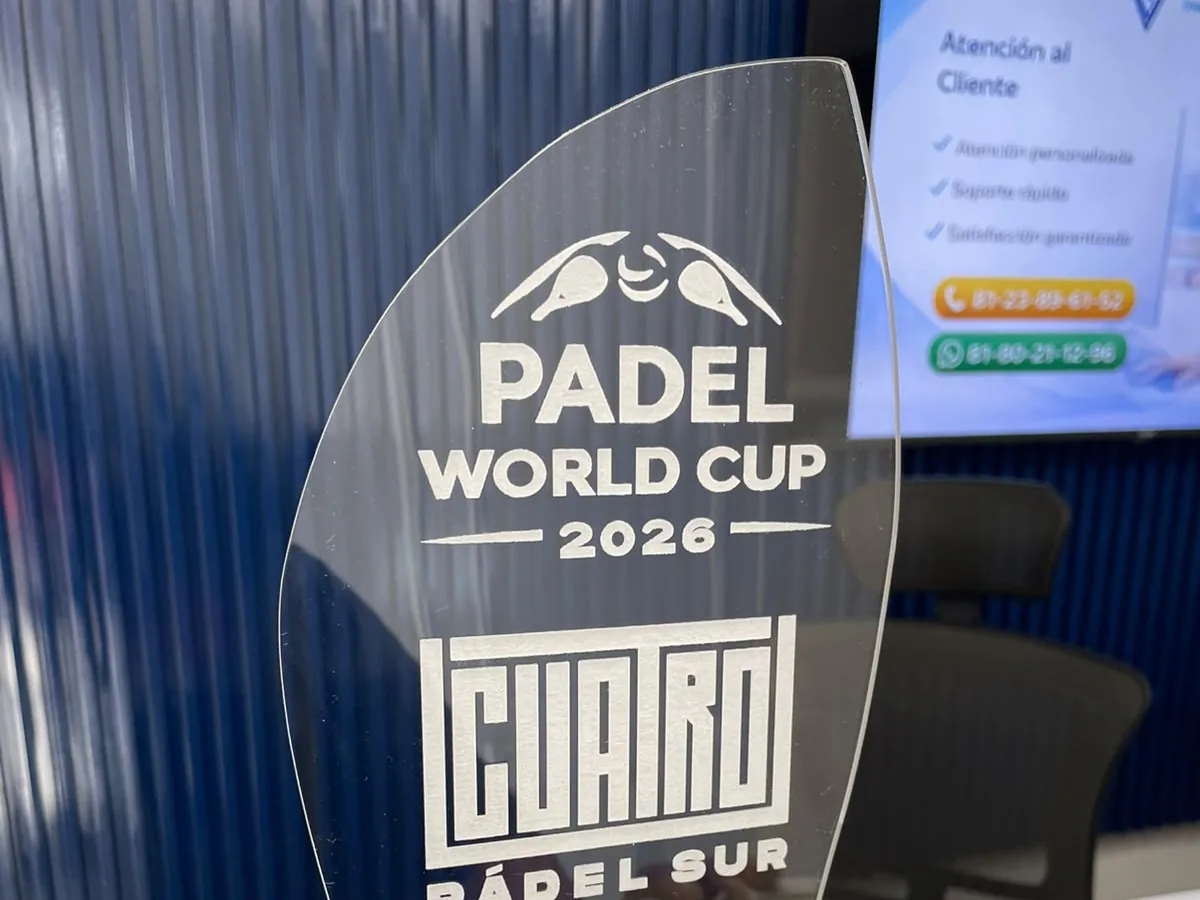 Trofeo de acrílico transparente con forma de vela, texto en blanco y base negra, sobre un mostrador