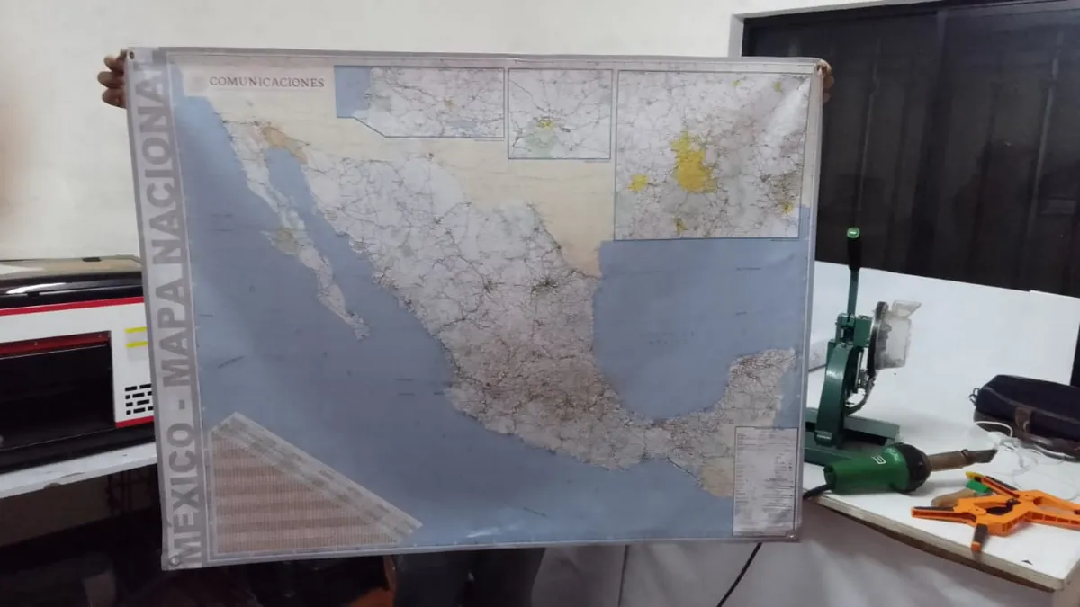 Mapa de México impreso en lona con ojillos en las esquinas, sostenido con las manos dentro del taller