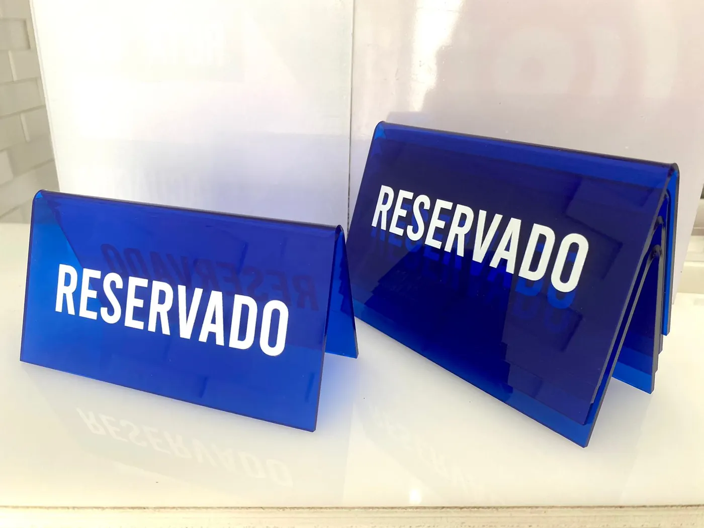 Letreros de mesa con la palabra RESERVADO en acrílico azul, cortados y doblados en el taller